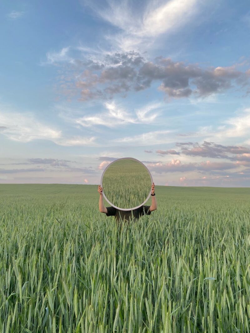 anonymous person in green grass with mirror